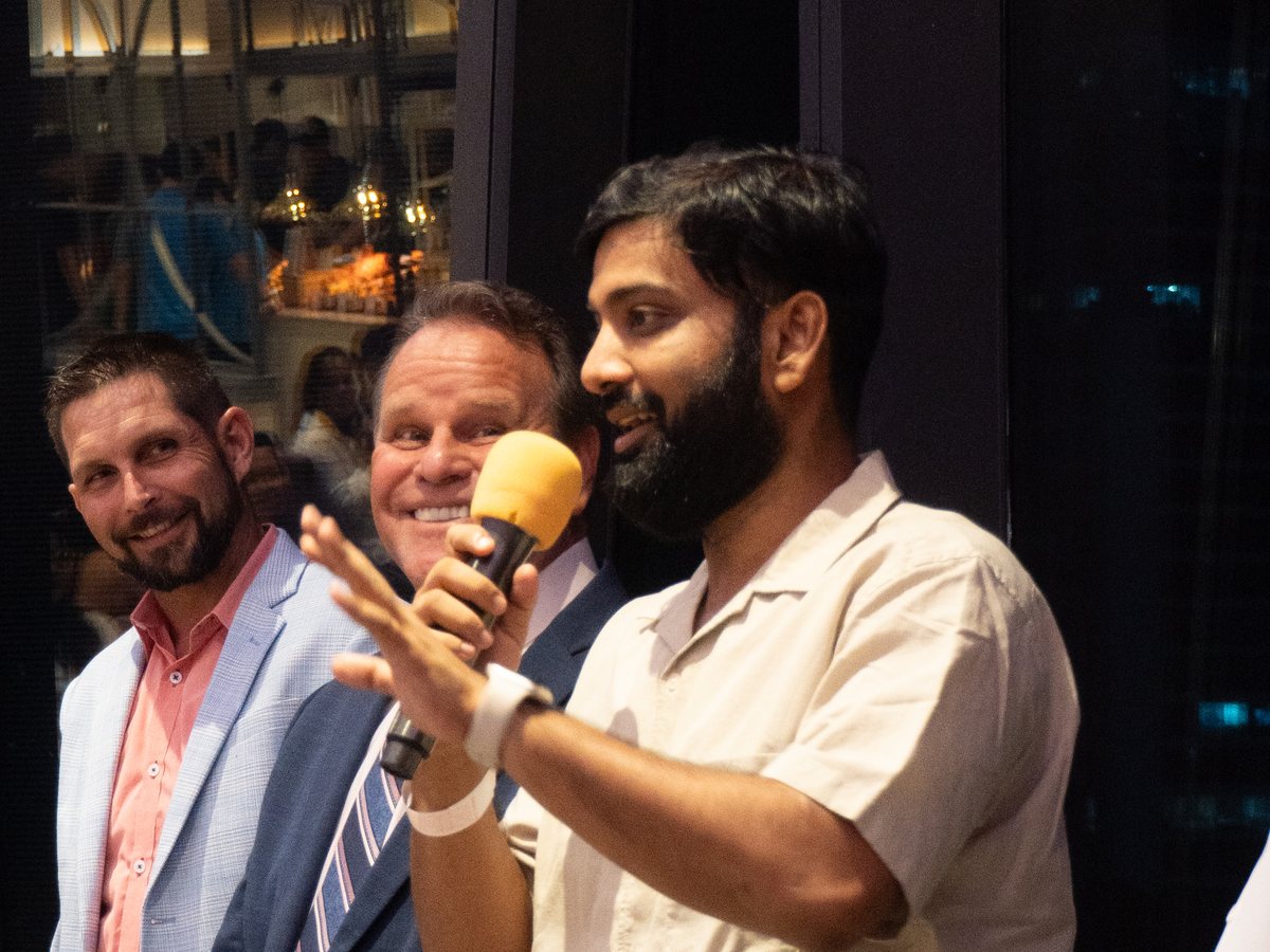 Sandeep Kumar Jha speaking into a microphone to a room, with the leadership team beside him